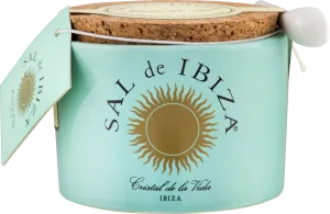 Helles, türkisfarbenes Keramikgefäß mit einem goldenen Sonnenemblem und Korkdeckel, begleitet von einem kleinen weißen Löffel. Ein Etikett ist an der Kordel befestigt.