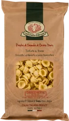 Papiertüte mit Sichtfenster, das gelbe, muschelähnliche Orecchiette-Nudeln zeigt; oben ein grünes Logo mit traditionellem Design.