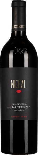 Dunkle Weinflasche mit schlichtem, elegantem Etikett in Schwarz und Gold, darauf ein markanter roter Punkt. Der Flaschenhals ist mit einem schwarzen und goldenen Siegel verziert.