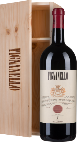 Flasche roten Weins mit cremefarbenem Etikett und rotem Wachssiegel, vor einer offenen hellen Holzkiste mit vertikalem Schriftzug platziert.