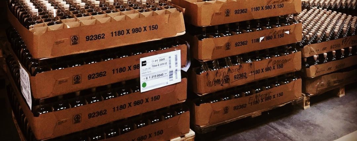 Holzfässer und Getränkekartons in einem Lagerregal gestapelt.