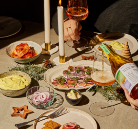 Festlich gedeckter Tisch mit Speisen, Kerzen und einem Glas, das gerade eingeschenkt wird.
