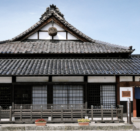 Traditionelles japanisches Gebäude mit schwarzem Ziegeldach und Holzelementen.