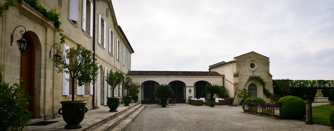 Historisches Herrenhaus mit eleganter Steinfassade und gepflegtem Innenhof voller Pflanzen.