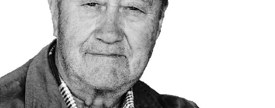 Älterer Mann mit Mütze und Jacke hält sich an einem Stock fest.