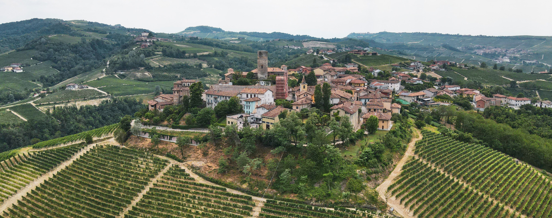 Mittelalterliches Dorf auf einem Hügel umgeben von grünen Weinbergen und Wäldern.