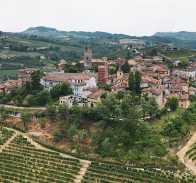 Mittelalterliches Dorf auf einem Hügel umgeben von grünen Weinbergen und Wäldern.