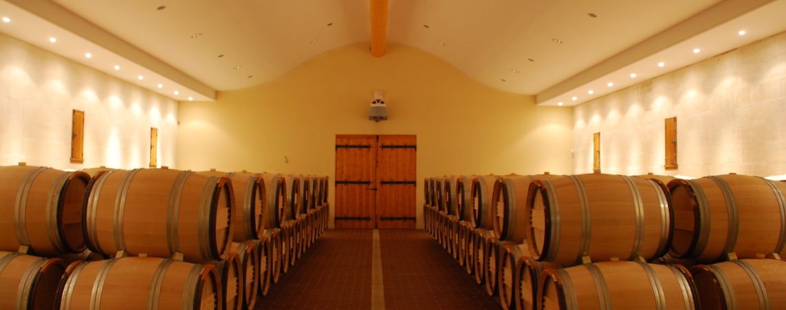 Weinkeller mit Holzfässern in symmetrischer Anordnung, warm beleuchtet.