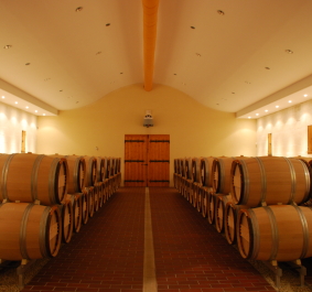 Weinkeller mit Holzfässern in symmetrischer Anordnung, warm beleuchtet.