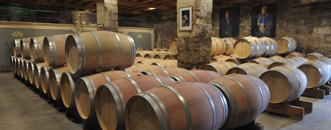 Weinkeller mit gestapelten Holzfässern auf Steinboden und gemauerten Wänden.