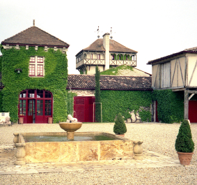 Historisches Gebäude mit Efeubewuchs, umgeben von Kiesweg und Zierpflanzen.