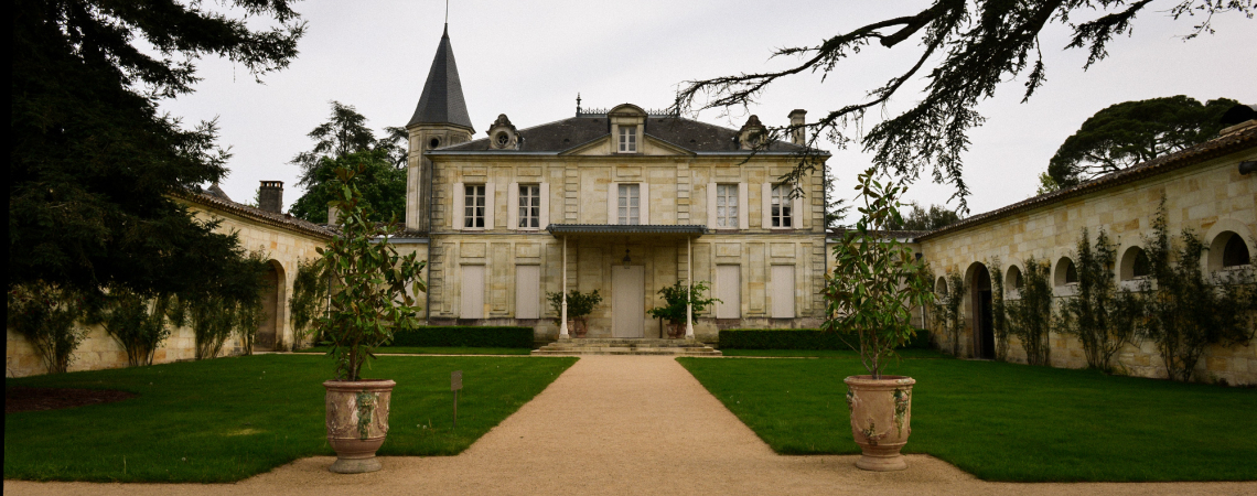 Historisches Schloss mit Türmen, zentralem Weg, umgeben von gepflegten Gärten und Bäumen.