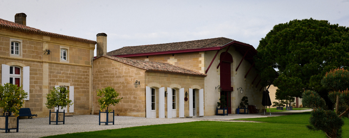 Sandstein-Gebäude in grüner Umgebung mit roten Dachakzenten.