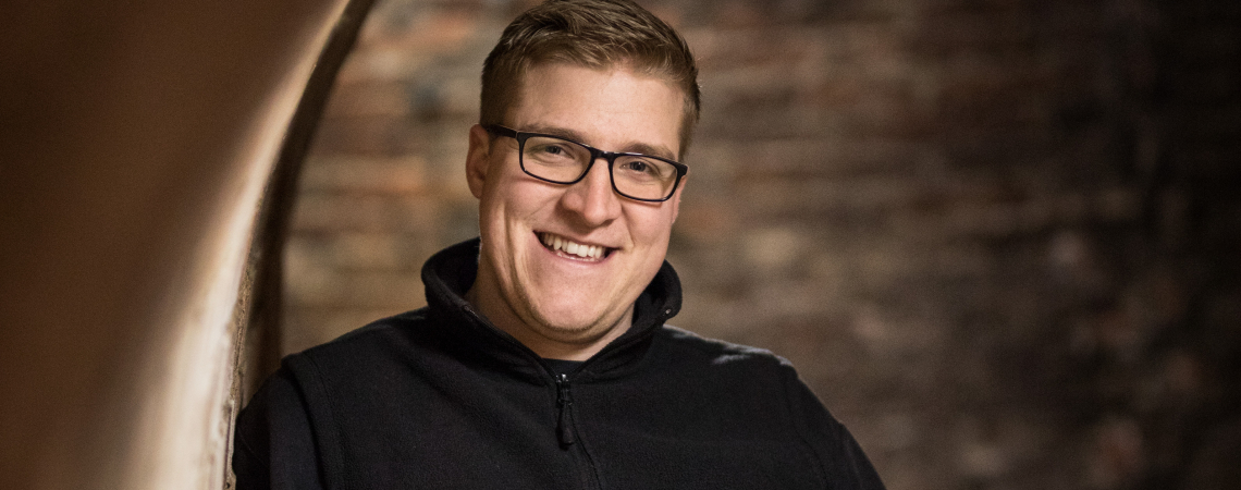 Mann in einer gewölbten, rustikalen Weinkellergasse, trägt dunkle Kleidung.