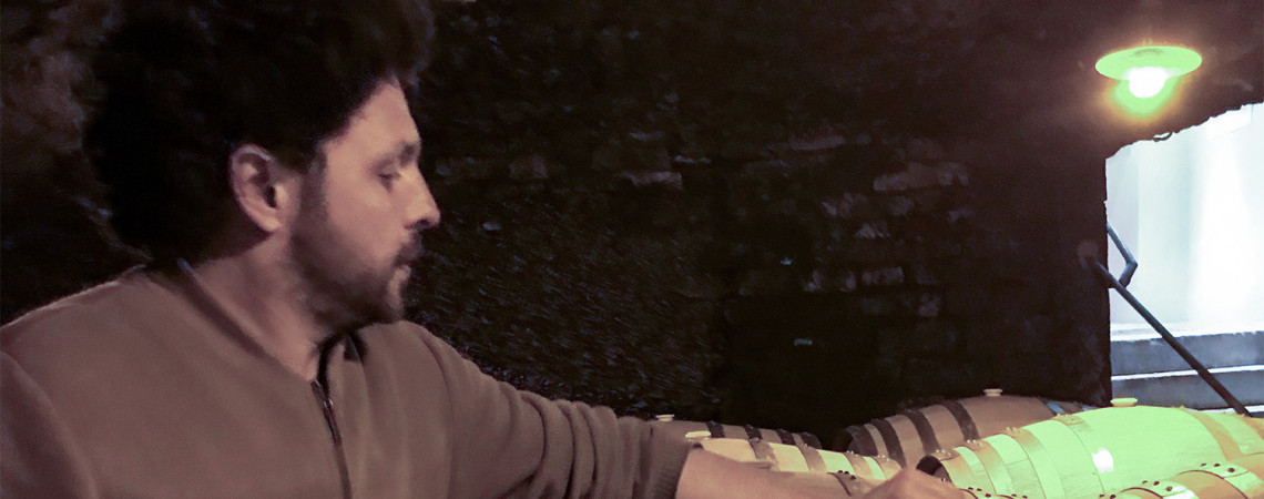 Person im Keller bei Holzfässern, gedämpfte Beleuchtung.