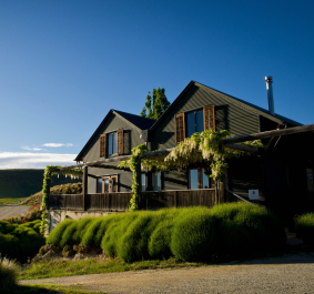 Modernes Landhaus mit grüner Fassade in malerischer Weinberglandschaft bei Sonnenuntergang.