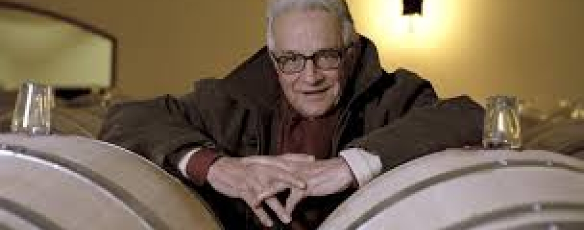 Mann mit Brille zwischen Weinfässern in einem gemütlichen Weinkeller.