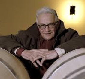 Mann mit Brille zwischen Weinfässern in einem gemütlichen Weinkeller.