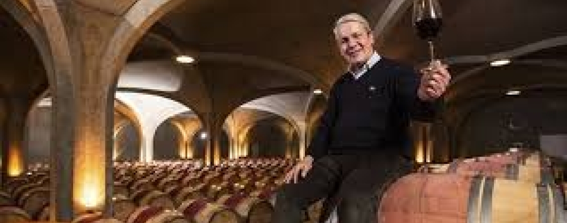 Mann hält Weinglas in einem Weinkeller mit vielen Fässern.