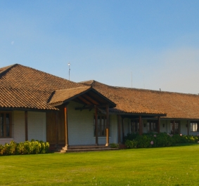 Langes Gebäude mit Ziegeldach, umgeben von grünem Rasen und Fahnen.