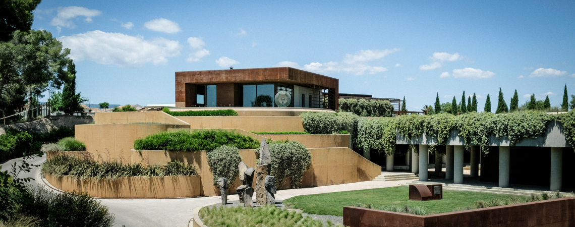 Modernes Gebäude mit grün bewachsenen Terrassen vor blauem Himmel.