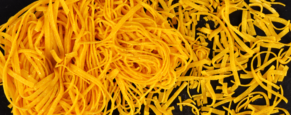 Zwei Arten von gelben, dünnen Nudeln, auf schwarzem Hintergrund.