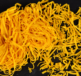 Zwei Arten von gelben, dünnen Nudeln, auf schwarzem Hintergrund.