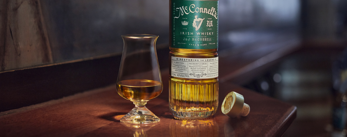 Whiskyflasche und Glas auf Holztisch, Hintergrund unscharf mit Kunstmotiv.