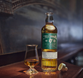 Whiskyflasche und Glas auf Holztisch, Hintergrund unscharf mit Kunstmotiv.