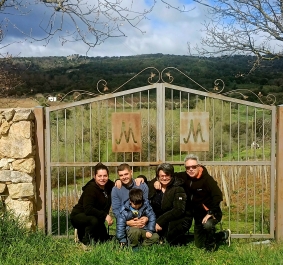 Steinmauer mit dekorativem Metalltor, umgeben von grüner Landschaft und Bäumen.