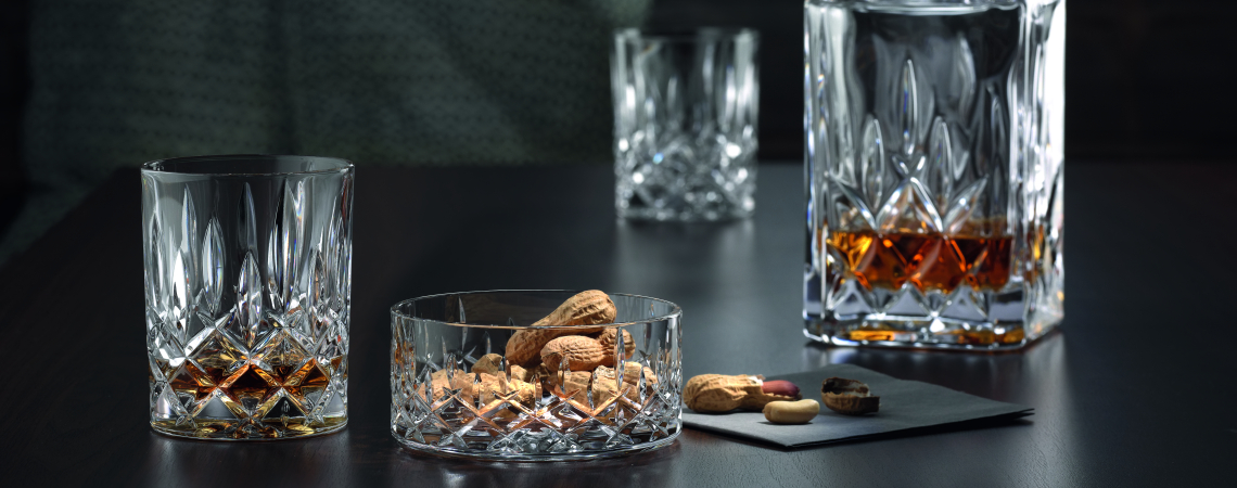 Kristallglas-Karaffe und Gläser auf dunklem Holztisch mit Nüssen dekoriert.