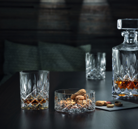 Kristallglas-Karaffe und Gläser auf dunklem Holztisch mit Nüssen dekoriert.