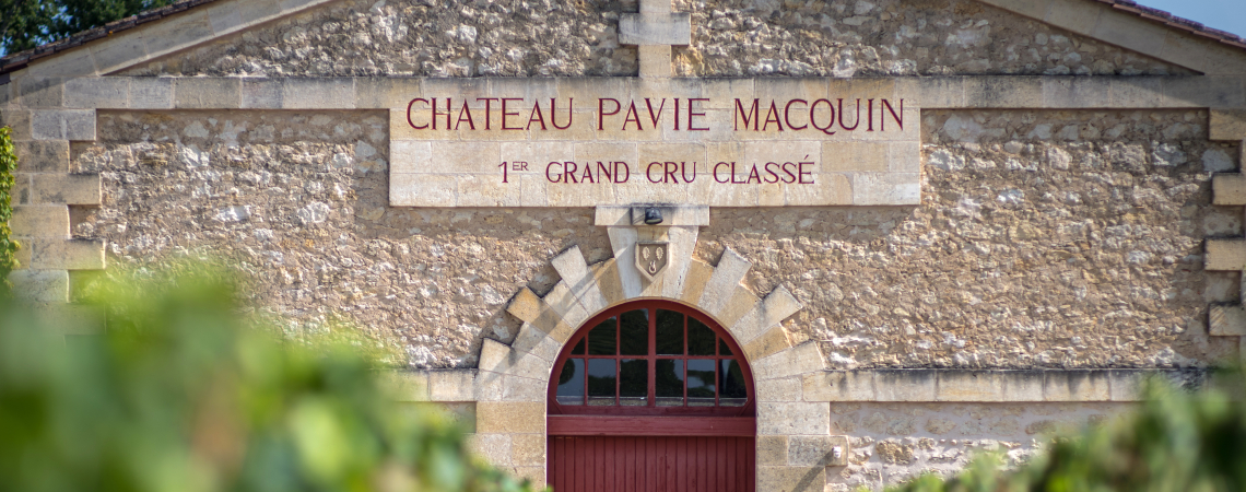 Historisches Steingebäude mit rotem Tor, umgeben von Weinreben.