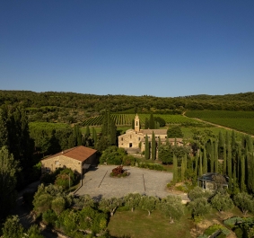 Luftaufnahme eines toskanischen Anwesens mit Zypressen und umliegenden Weinbergen.