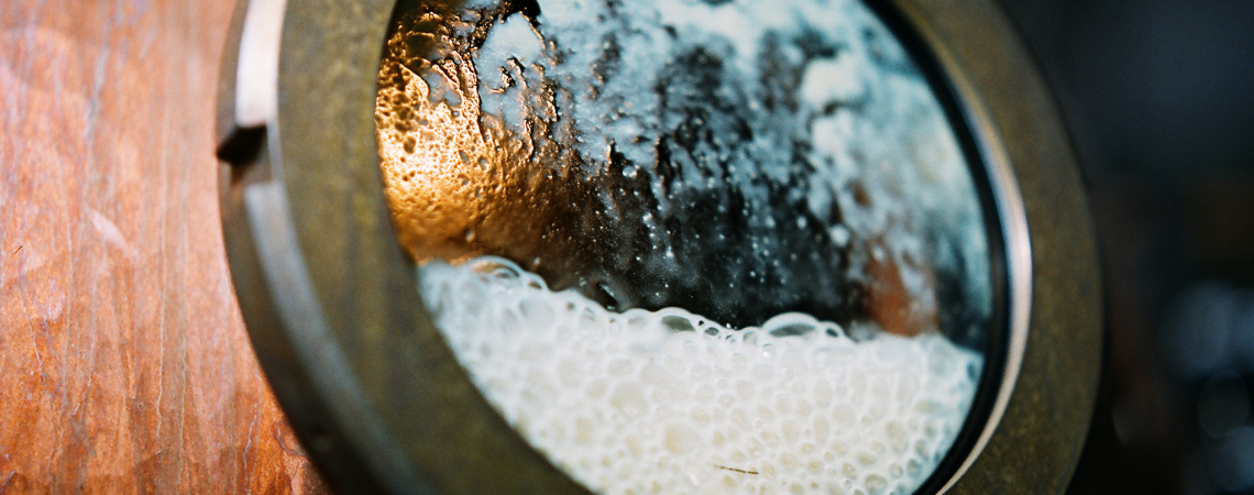 Metallfenster an brauner Holzfassade mit Schaum und Kondensation.