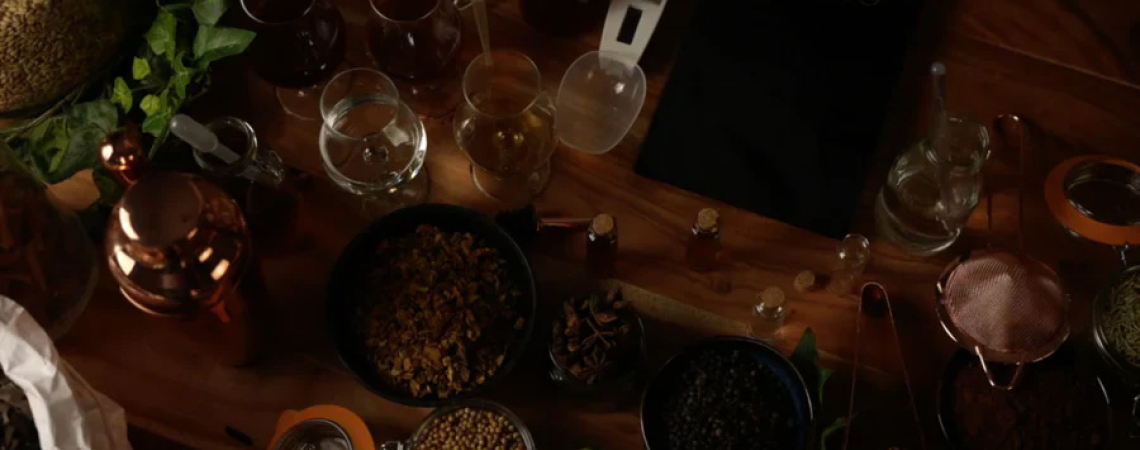 Verschiedene Gewürze, Gläser und Küchenutensilien auf einem rustikalen Holztisch arrangiert.