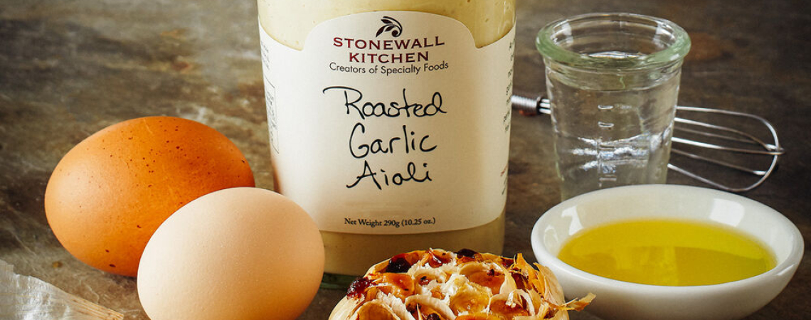 Glas Aioli mit Knoblauch, Eiern, Öl und Salz auf rustikalem Hintergrund.