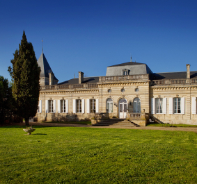Historisches Schloss mit symmetrischen Fassaden, Türmen und gepflegtem Rasen, strahlt Eleganz aus.