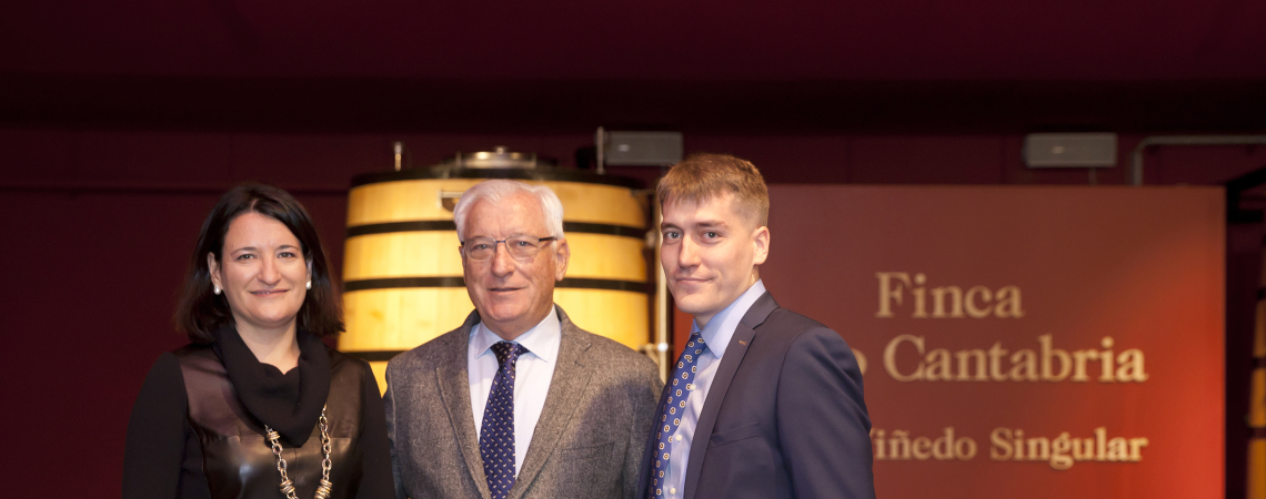 Drei Personen vor Weinfässern in stilvollem, elegantem Ambiente.