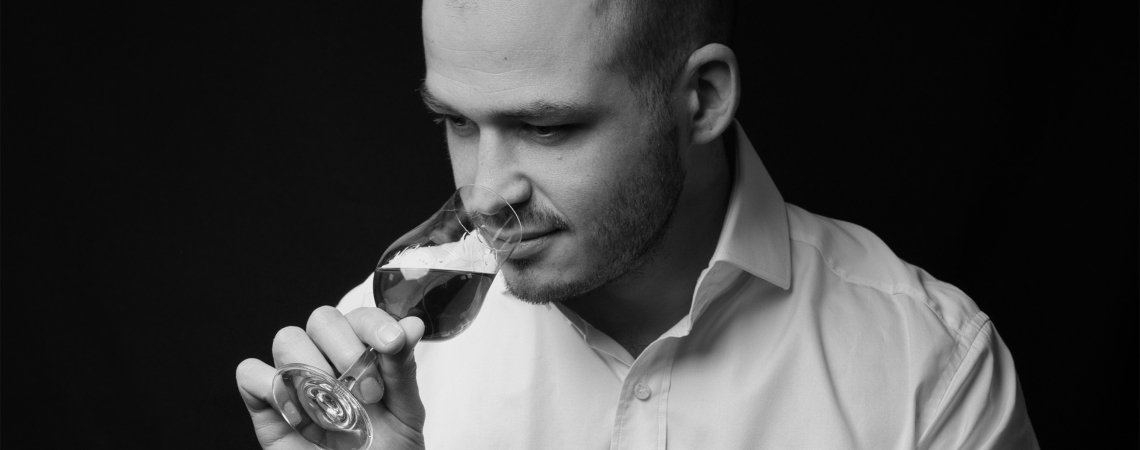 Mann in Hemd genießt Drink, sitzt auf Fass, hält Flasche.