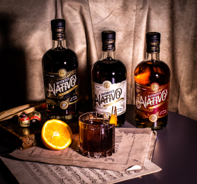 Drei Rumflaschen mit Cocktail, Schokolade und Orangenscheibe auf stilvollem Hintergrund.