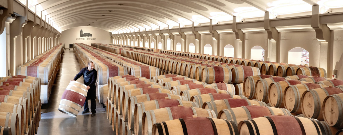 Weinkeller mit vielen Holzfässern, Person rollt ein Fass.