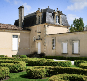 Herrenhaus mit klassischer Fassade und gepflegtem Garten im französischen Stil.