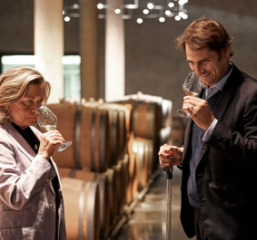 Zwei Personen verkosten Wein in einem stilvollen Weinkeller mit Holzfässern.