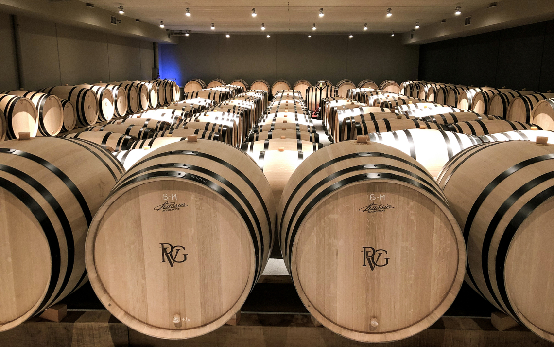 Viele Holzfässer in einem gut beleuchteten Lagerraum.