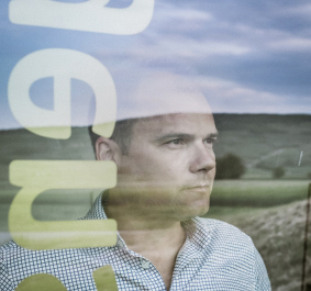 Mann hinter Glas mit Landschaftsreflektion und überlagerndem Text.