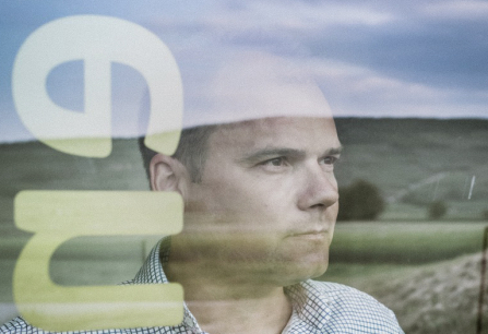 Mann hinter Glas mit Landschaftsreflektion und überlagerndem Text.