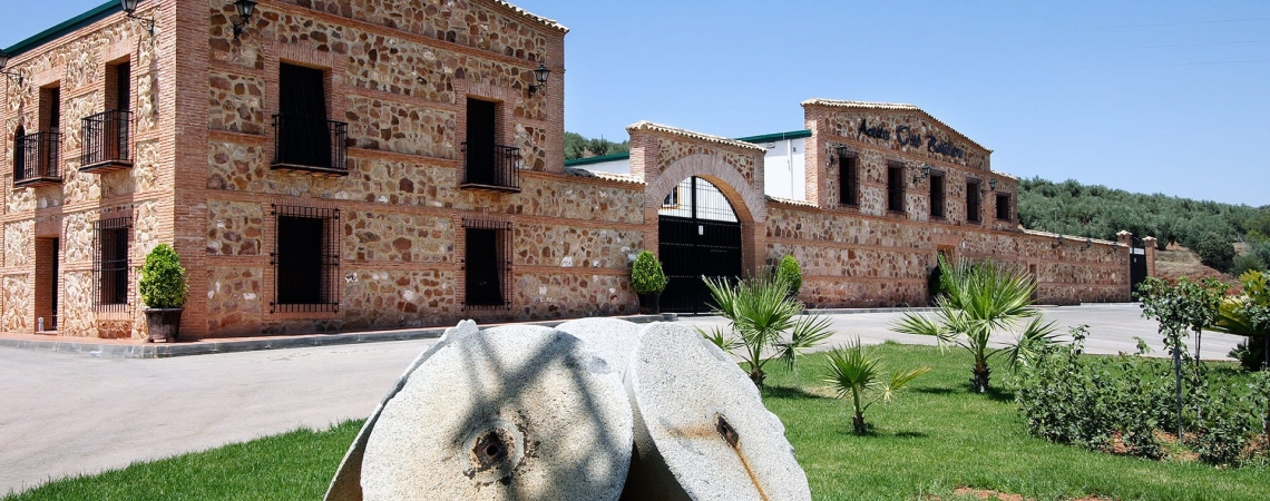 Historisches Backsteingebäude mit altem Mühlstein im gepflegten Vorgarten.