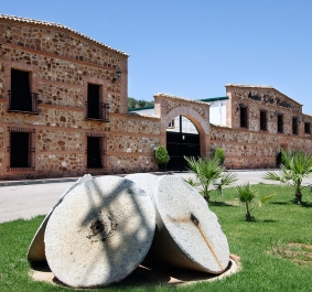 Historisches Backsteingebäude mit altem Mühlstein im gepflegten Vorgarten.