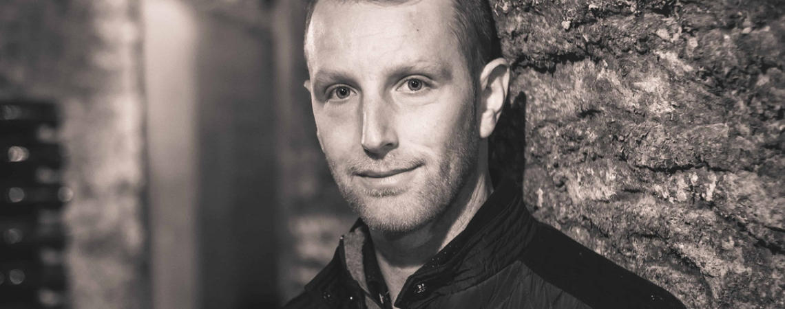 Schwarz-weiß Porträt eines Mannes in einer rustikalen, steinernen Umgebung.